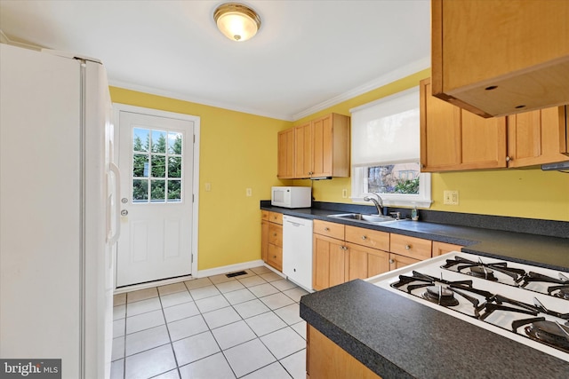 kitchen featuring white appliances, a sink, a healthy amount of sunlight, dark countertops, and crown molding