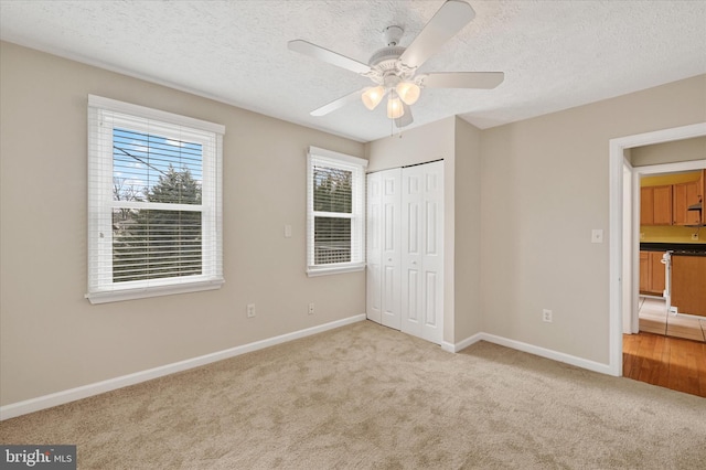 unfurnished bedroom with a textured ceiling, carpet floors, a closet, and baseboards