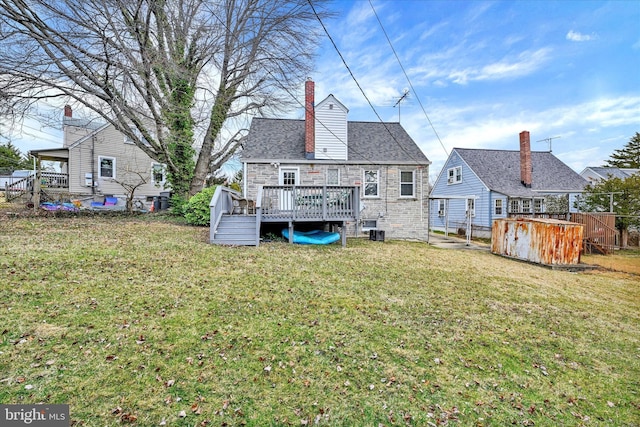 rear view of property featuring a chimney, central air condition unit, a lawn, stone siding, and a wooden deck