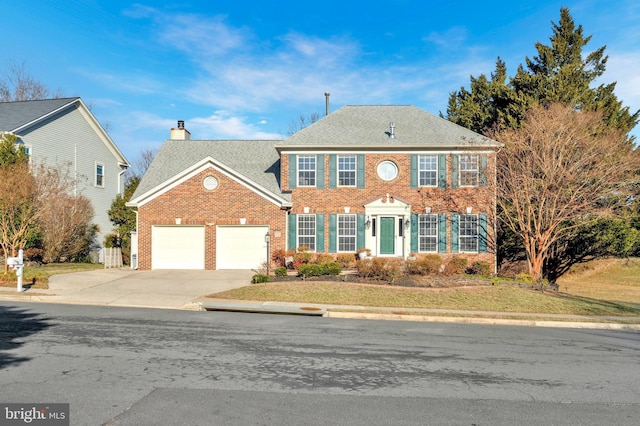 view of front facade with driveway, a garage, brick siding, a chimney, and a front yard