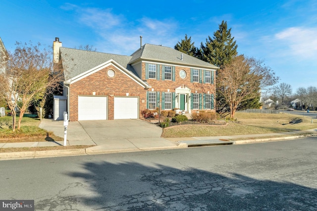 view of front facade with driveway, a chimney, roof with shingles, an attached garage, and brick siding