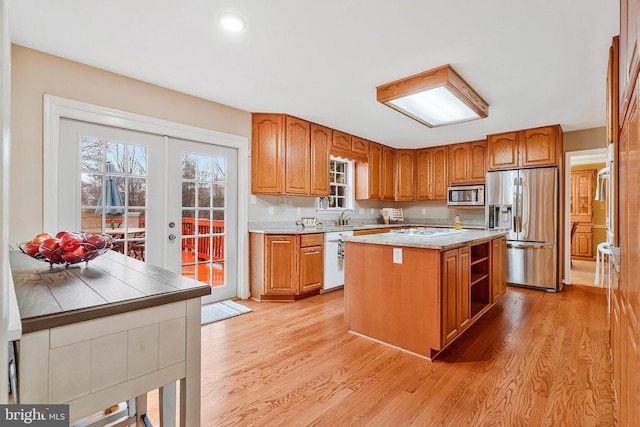 kitchen featuring french doors, stainless steel appliances, brown cabinetry, a kitchen island, and light wood-type flooring