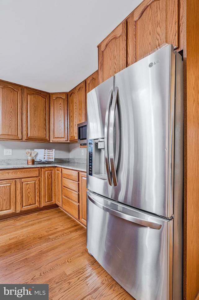 kitchen with brown cabinetry, stainless steel appliances, and light wood-style floors