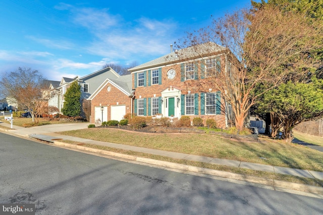 colonial house featuring driveway, an attached garage, a front yard, and brick siding