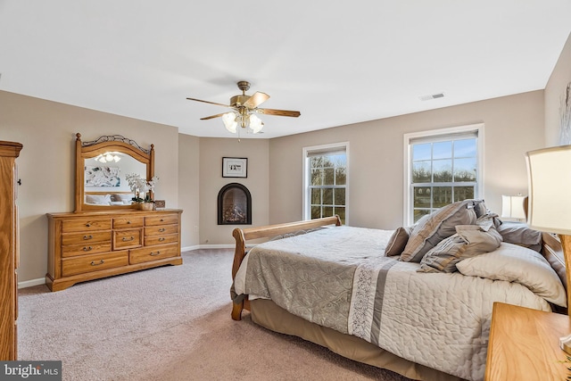 bedroom featuring ceiling fan, a fireplace, carpet flooring, visible vents, and baseboards