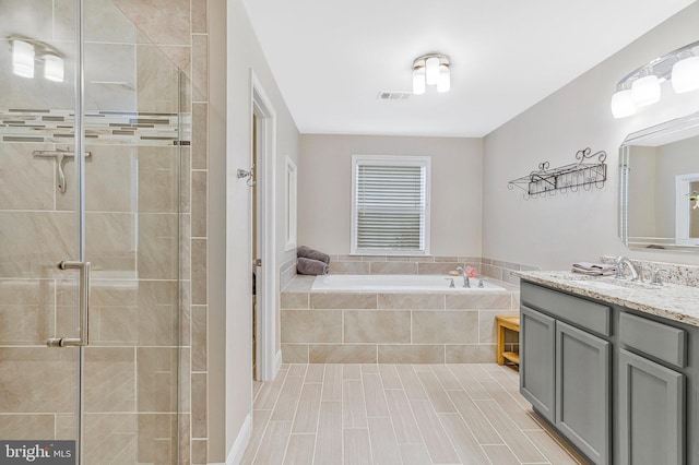 full bathroom featuring a stall shower, visible vents, a garden tub, and vanity