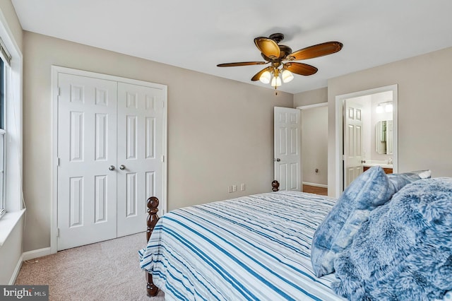 carpeted bedroom with a closet, ensuite bath, a ceiling fan, and baseboards