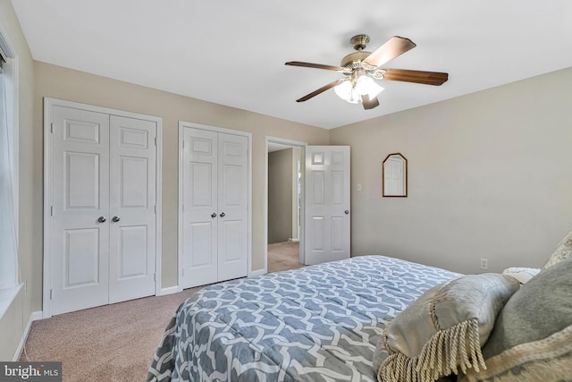 carpeted bedroom featuring ceiling fan, two closets, and baseboards