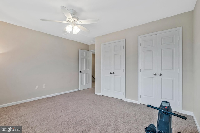 unfurnished bedroom with carpet flooring, two closets, a ceiling fan, and baseboards