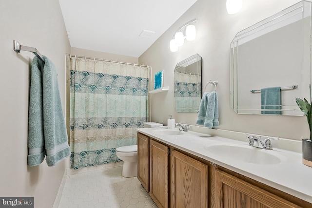 bathroom featuring double vanity, a sink, toilet, and tile patterned floors