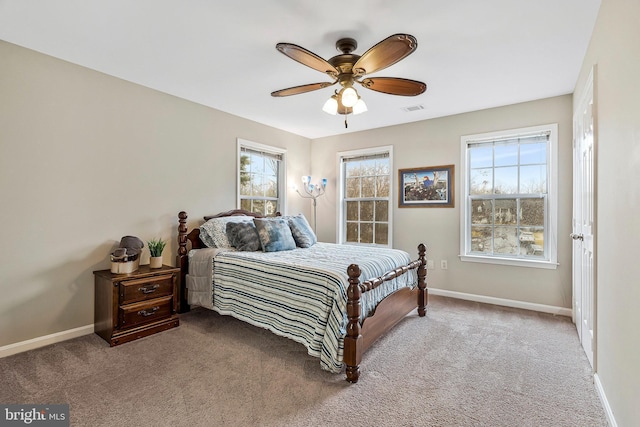 carpeted bedroom featuring a ceiling fan, multiple windows, visible vents, and baseboards