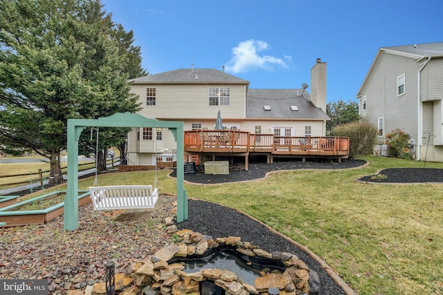 back of property with a lawn, a chimney, and a wooden deck