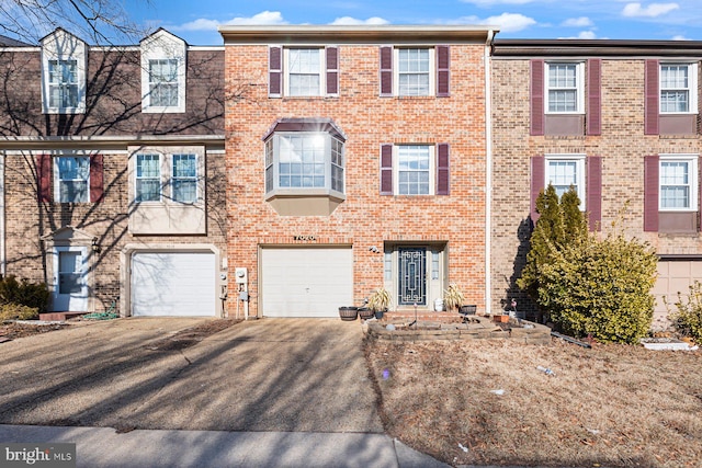 townhome / multi-family property featuring a garage, driveway, and brick siding