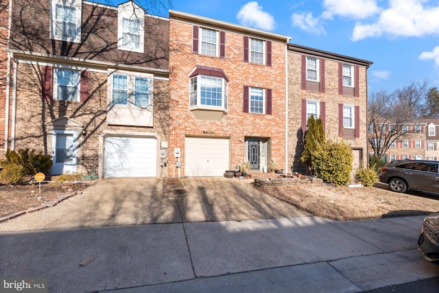 view of property featuring driveway, an attached garage, and brick siding