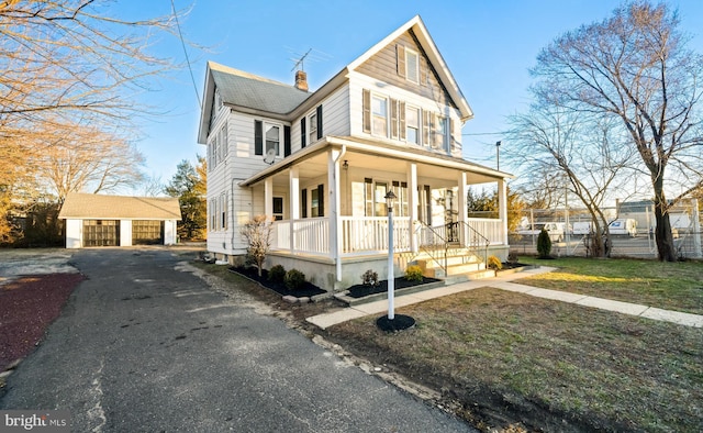 view of front of house with covered porch, a chimney, an outdoor structure, and a garage