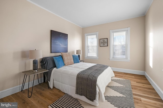 bedroom featuring crown molding, wood finished floors, and baseboards
