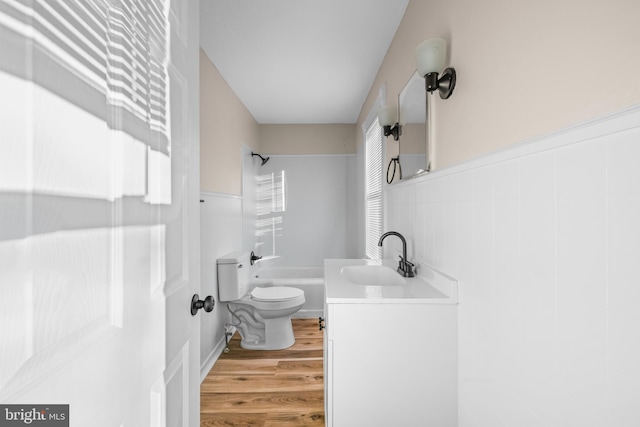 full bathroom with toilet, washtub / shower combination, wood finished floors, and vanity
