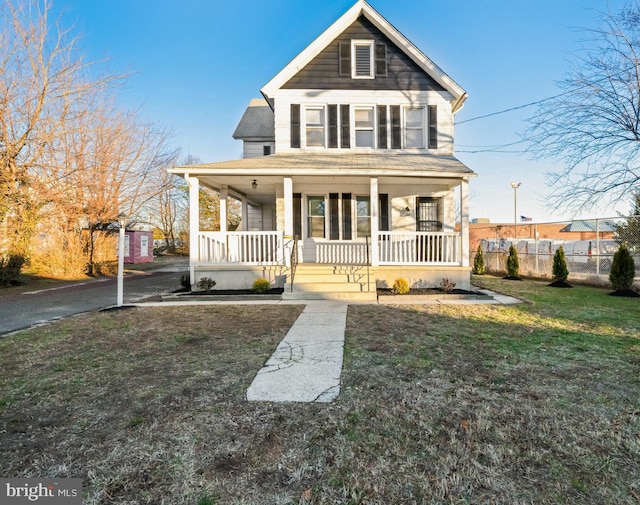 view of front facade featuring a porch, a front yard, and fence