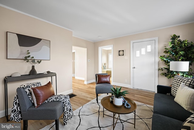 living area with ornamental molding, light wood-style flooring, and baseboards