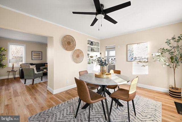 dining area featuring crown molding, light wood-type flooring, and baseboards