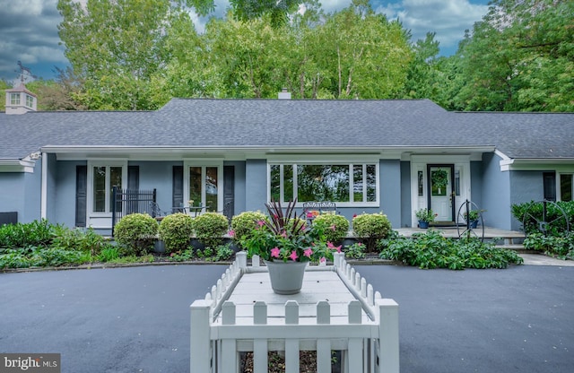 ranch-style home with stucco siding and roof with shingles