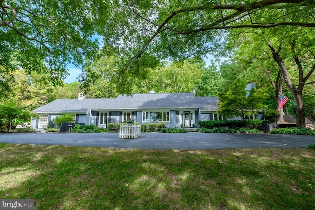 ranch-style home featuring aphalt driveway and a front lawn