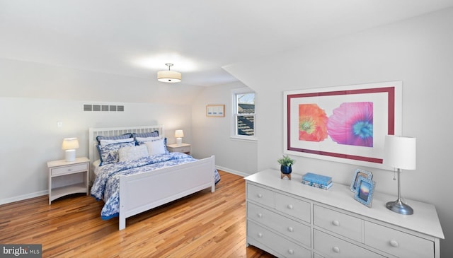 bedroom featuring lofted ceiling, baseboards, visible vents, and light wood finished floors