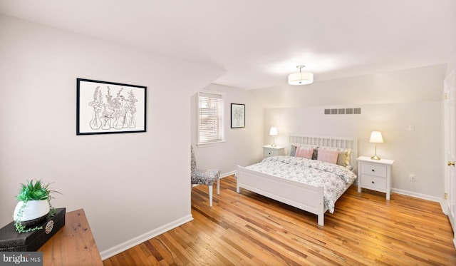 bedroom featuring visible vents, light wood-type flooring, and baseboards