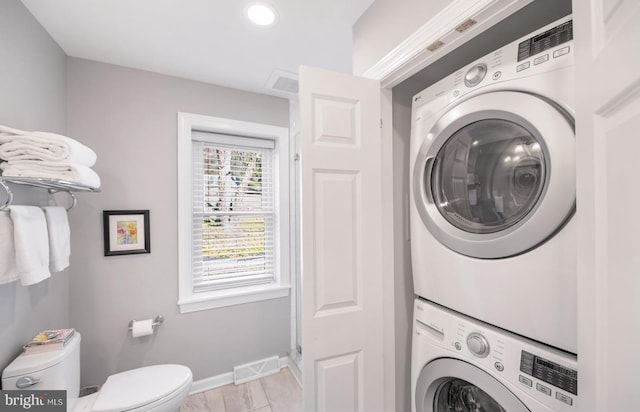 clothes washing area featuring baseboards, stacked washer / dryer, laundry area, and visible vents