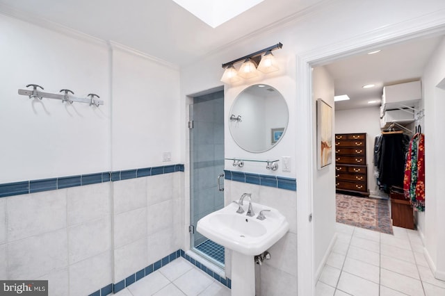 full bath featuring a stall shower, ornamental molding, tile patterned flooring, a walk in closet, and tile walls