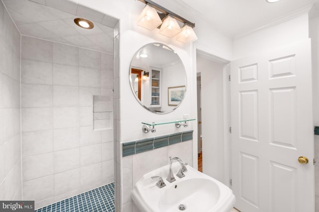 bathroom with a sink, tile walls, and ornamental molding
