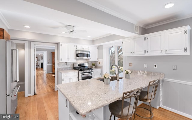 kitchen featuring a sink, stainless steel appliances, a peninsula, and ornamental molding