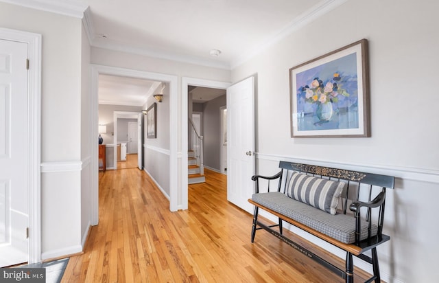 hallway with crown molding, light wood-type flooring, and stairs