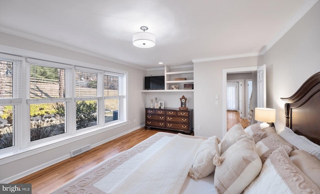 bedroom with visible vents, crown molding, baseboards, and wood finished floors