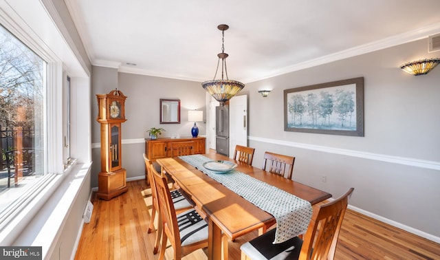 dining space with crown molding, baseboards, light wood-type flooring, and visible vents