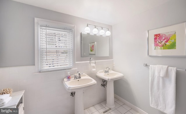 bathroom featuring tile patterned flooring, tile walls, a wainscoted wall, and a sink
