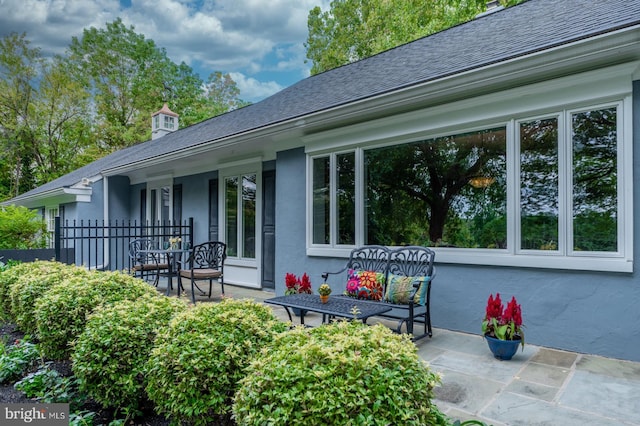 back of property with stucco siding and roof with shingles