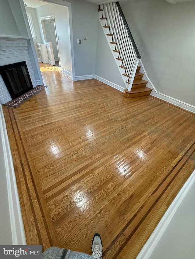 unfurnished living room featuring a brick fireplace and light hardwood / wood-style flooring