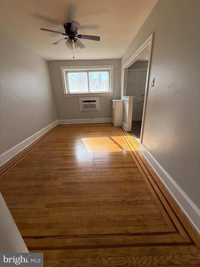 spare room featuring ceiling fan, a wall unit AC, and light hardwood / wood-style flooring