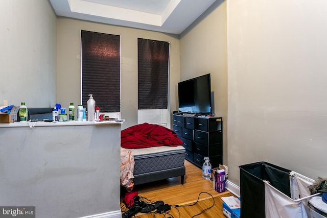 bedroom with hardwood / wood-style floors and a raised ceiling