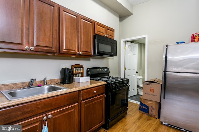 kitchen with light wood-type flooring, sink, and black appliances