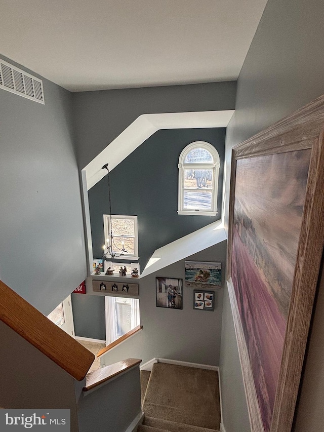 stairway with carpet flooring and a chandelier