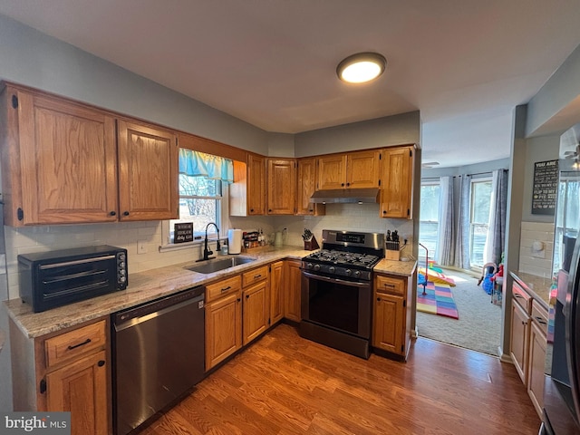 kitchen with sink, hardwood / wood-style flooring, dishwasher, backsplash, and stainless steel range with gas stovetop