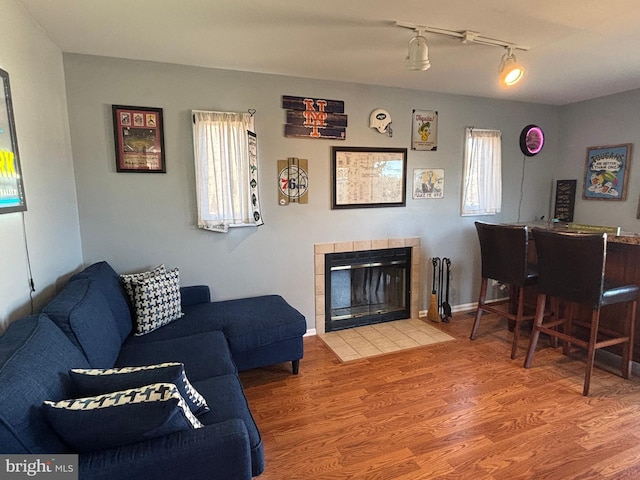 living room with hardwood / wood-style floors, a tile fireplace, and indoor bar