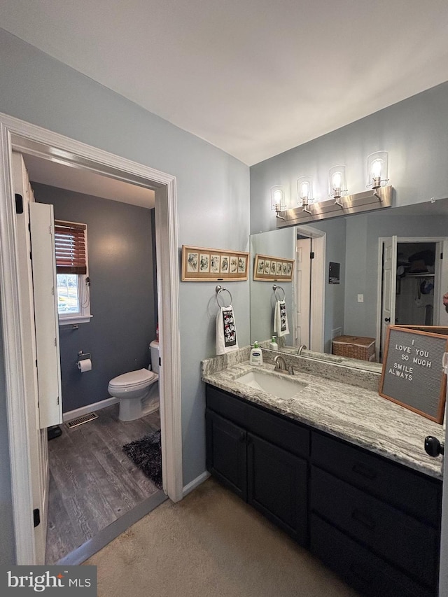 bathroom with vanity, toilet, and wood-type flooring