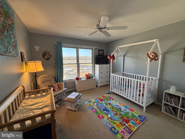 carpeted bedroom with ceiling fan and a crib