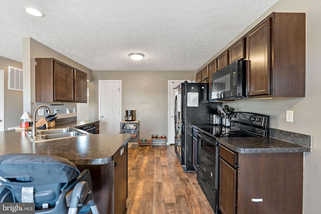 kitchen featuring sink, dark hardwood / wood-style flooring, black appliances, kitchen peninsula, and dark brown cabinetry