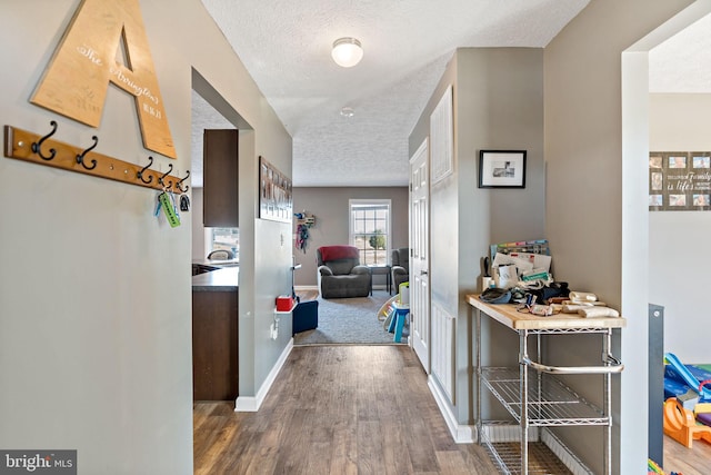 hallway with a textured ceiling and dark hardwood / wood-style floors