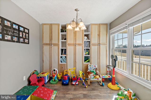 game room with an inviting chandelier, wood-type flooring, and a textured ceiling