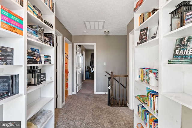 corridor with carpet floors and a textured ceiling